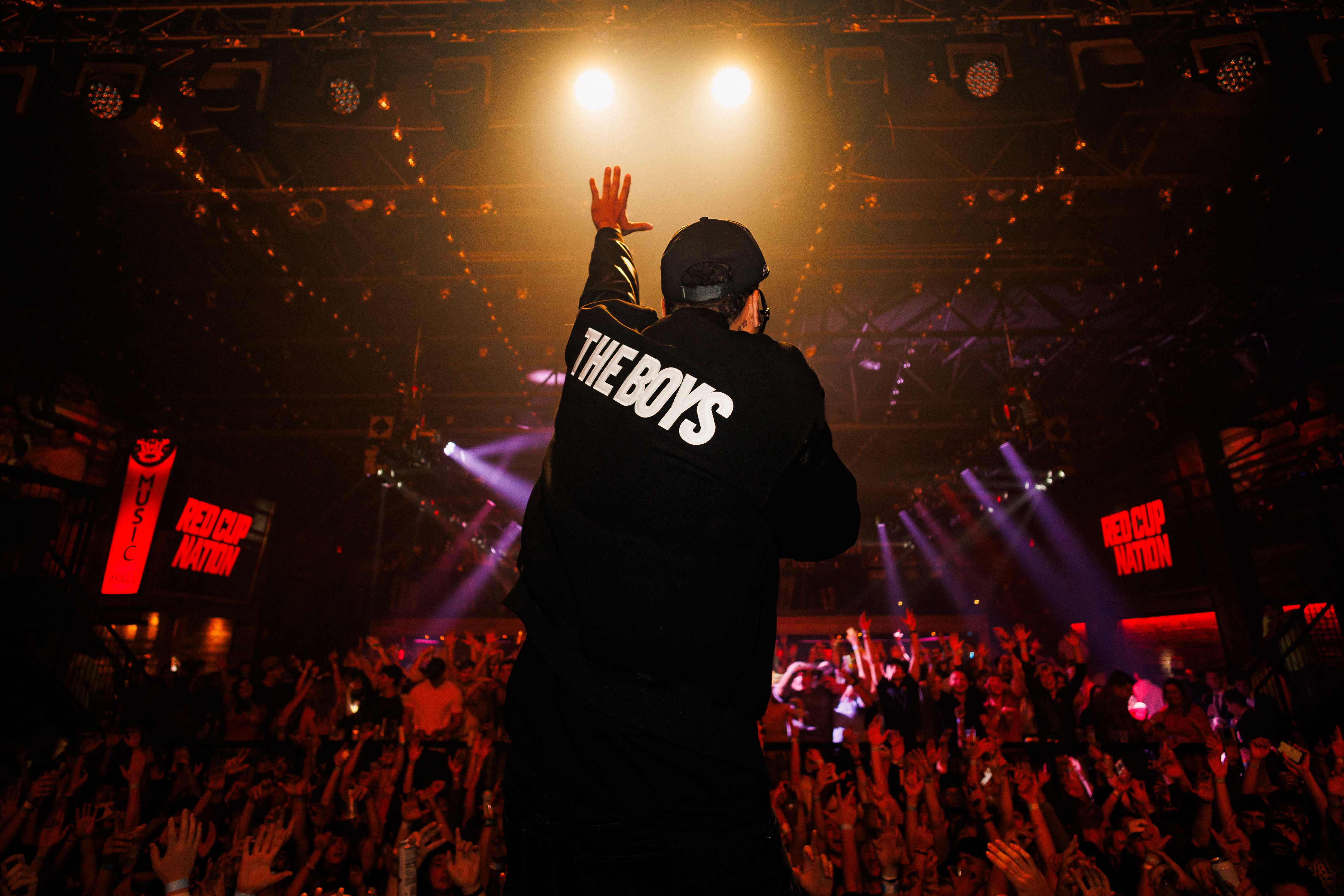 Performer wearing The Boys jacket on stage with spotlights